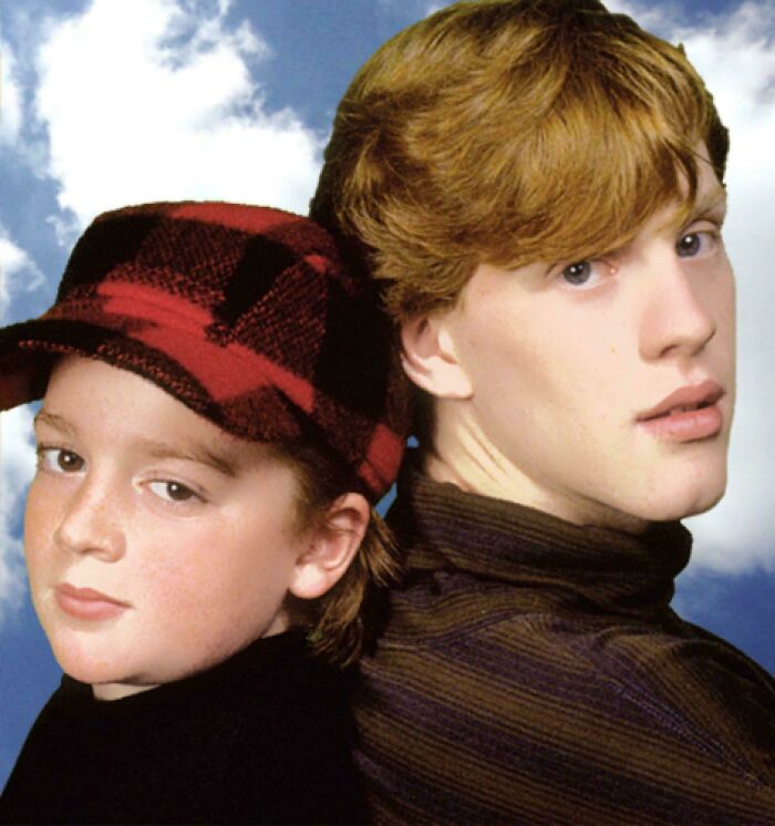 Two kids from the '90s, one in a red plaid hat, against a cloudy sky backdrop.