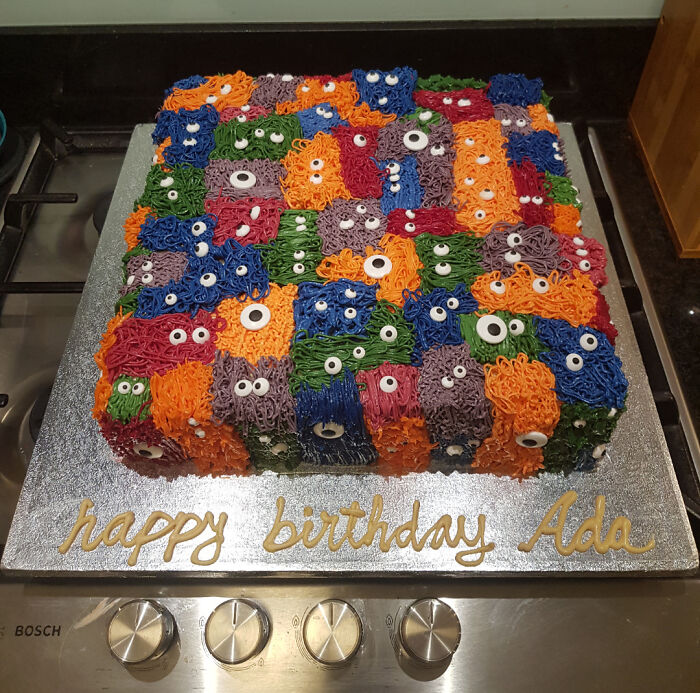 Colorful square birthday cake with multi-colored monster faces made of icing, showcasing incredible bakes with creative details.
