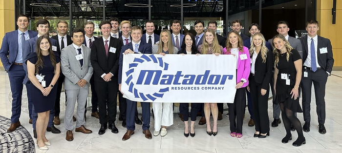 Group of professionals in business attire holding Matador Resources Company banner, illustrating outrageous job requirements challenge.