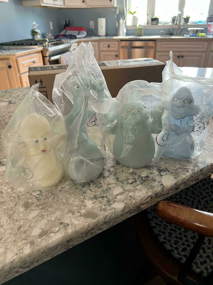 Four '90s ghost toys in plastic bags on a kitchen counter.