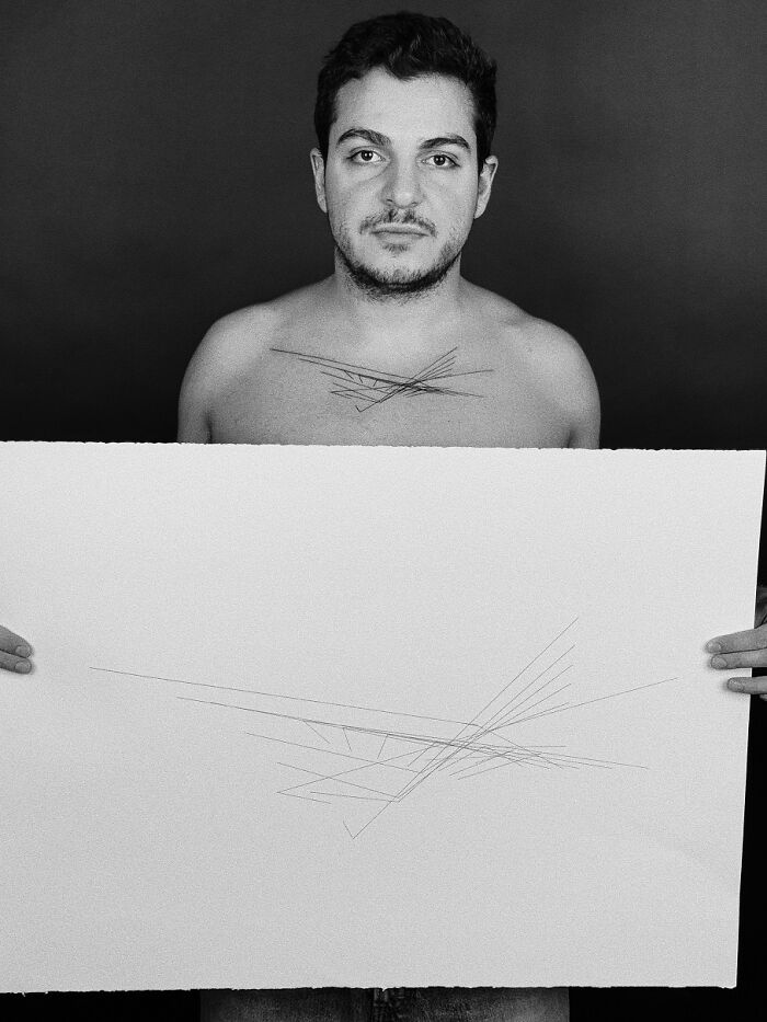 Man displaying tattoo inspired by unique brain activity pattern on chest, holding matching abstract artwork.