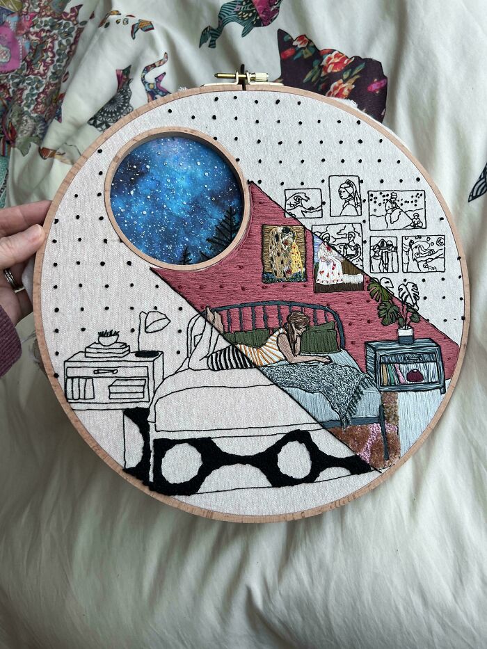 Hand holding embroidery hoop showcasing beautiful embroidery skills with a detailed night sky and cozy bedroom scene.