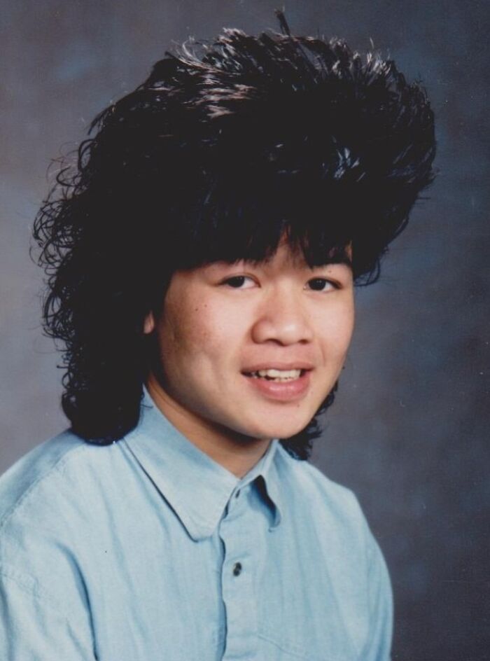 Person with big 1980s hairstyle wearing a blue shirt, showcasing epic hair disasters.