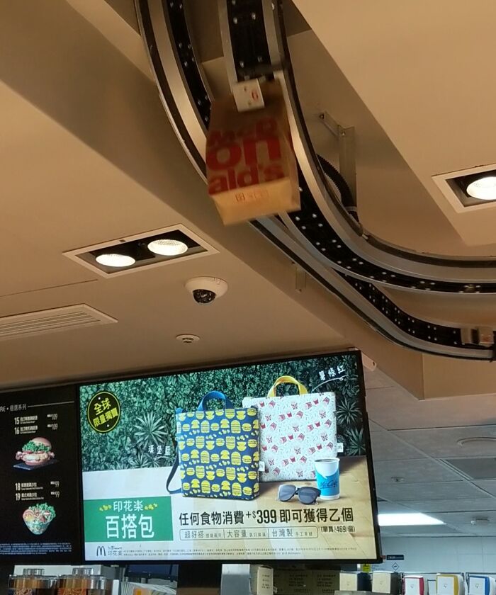 McDonald's bag on a conveyor, tourist-interesting experiences, with a screen showing promotional items in a restaurant.