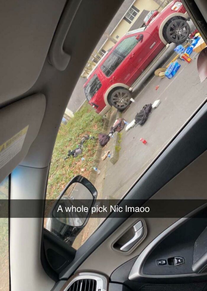 A red SUV parked with scattered items nearby seen from inside another car, featuring a misspelled phrase.
