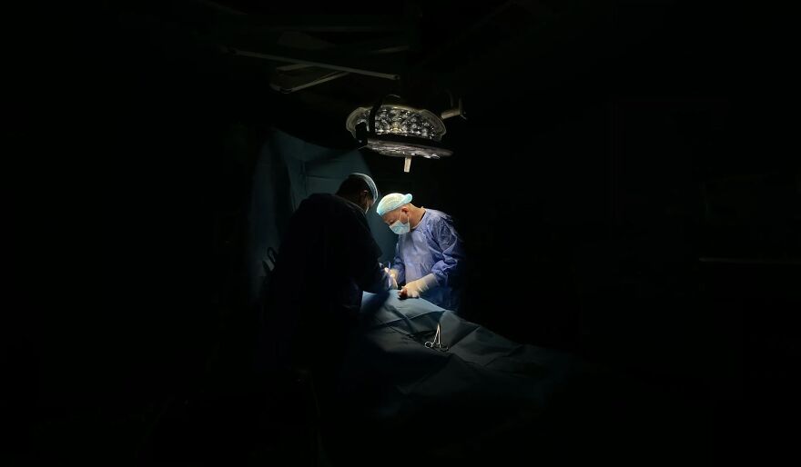 Surgeons in dimly lit operating room, highlighting ethical dilemmas in medical practice.