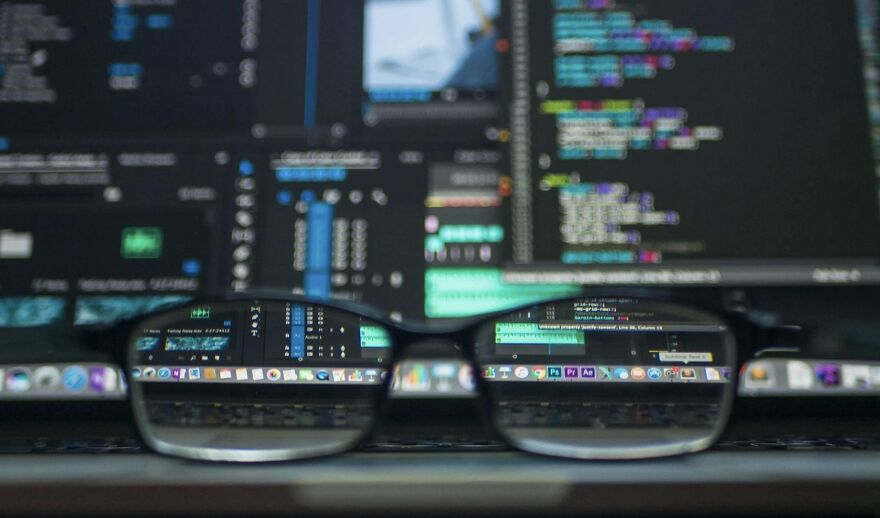 Glasses in front of a computer screen displaying complex code, symbolizing ethical dilemmas in technology.