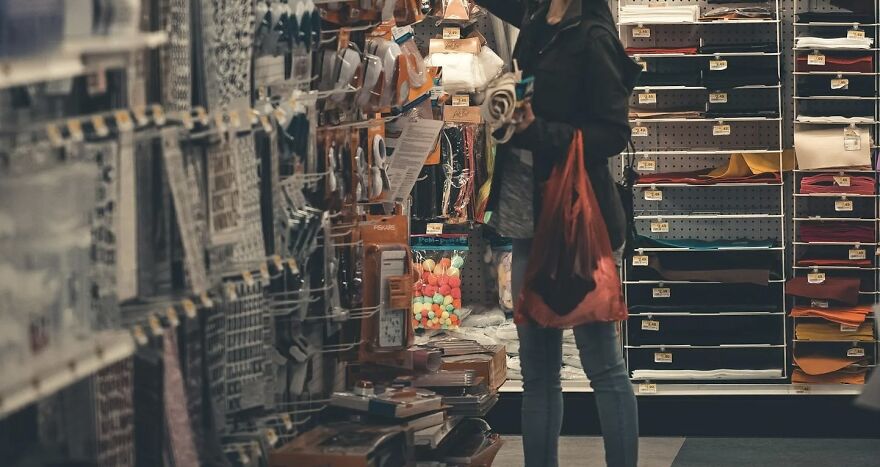 Person pondering choices in a store aisle, holding a bag, illustrating ethical dilemmas in everyday decisions.