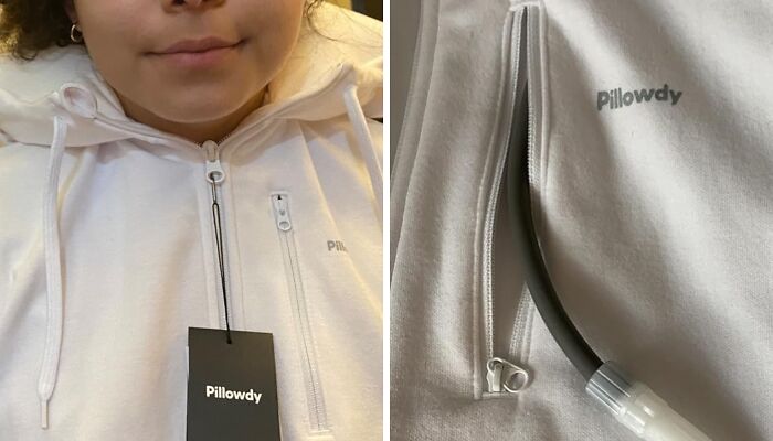 Person wearing a black hoodie stands indoors with hands in pockets, showcasing innovative clothing design.