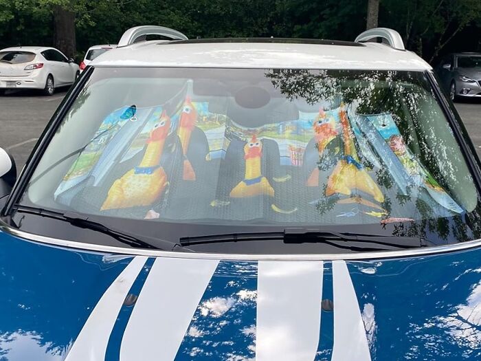 Car windshield sunshade featuring Archie Mcphee items, depicting rubber chickens in the seats.