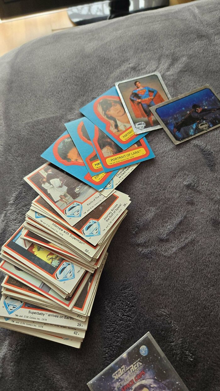 Vintage '90s trading cards, including Superman, spread on a gray surface.