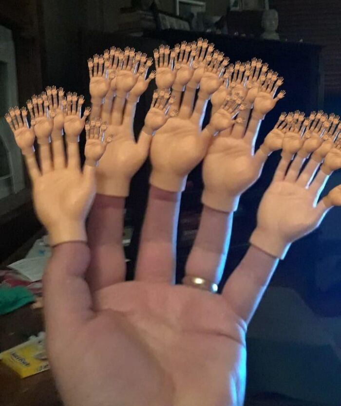 A hand covered in layers of tiny plastic hands, showcasing unique Archie Mcphee items.