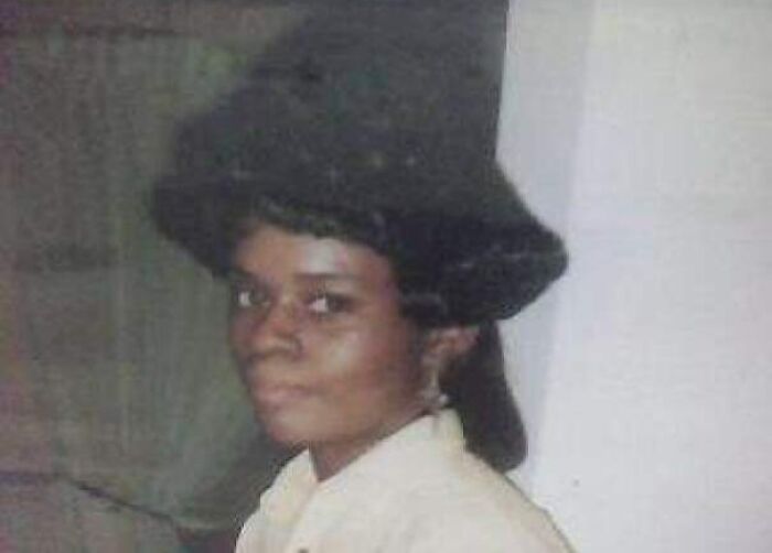 1980s hair disasters: Woman with high hairstyle posing indoors, showcasing epic fashion.