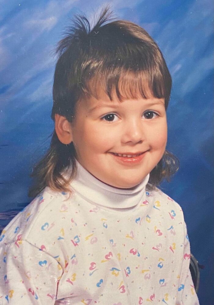 Child with a mullet hairstyle, smiling against a blue background, embodying epic hair disasters from the 1980s and 1990s.