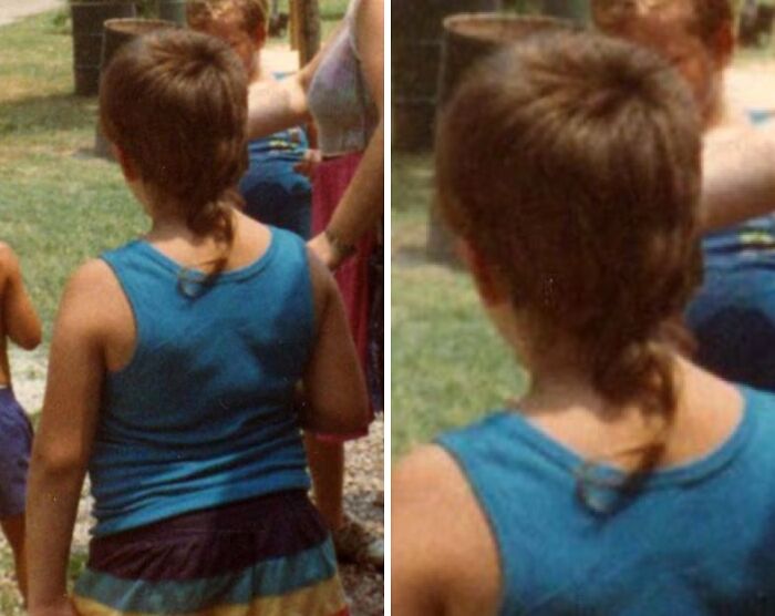 Child in a blue tank top with 1980s hairstyle, standing outdoors with people in the background.