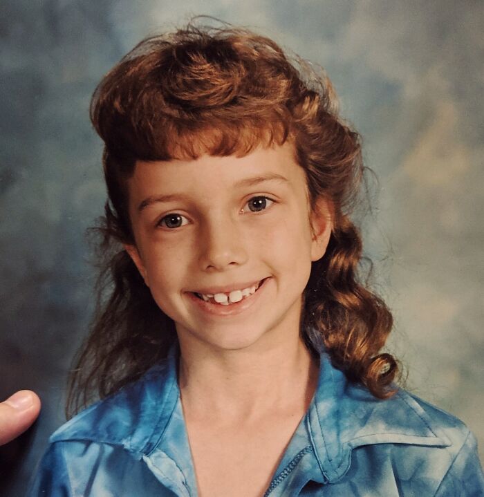 Young girl with 1980s hairstyle, wearing a blue shirt, showing an epic hair disaster characteristic of the era.