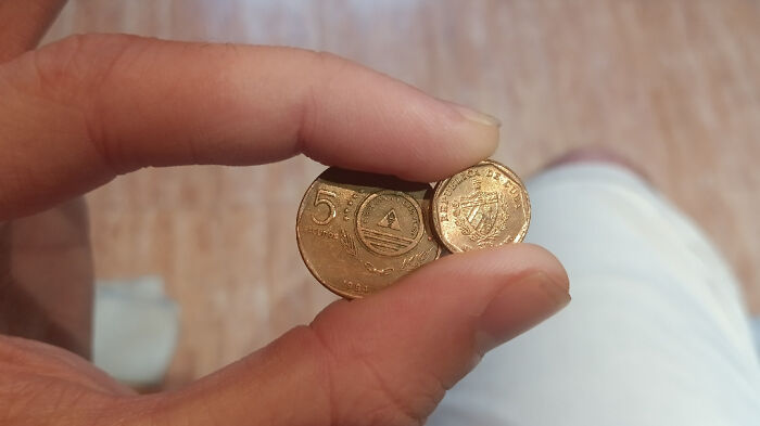 Fingers holding small coins, representing mildly infuriating server tips with minimal gratuity.