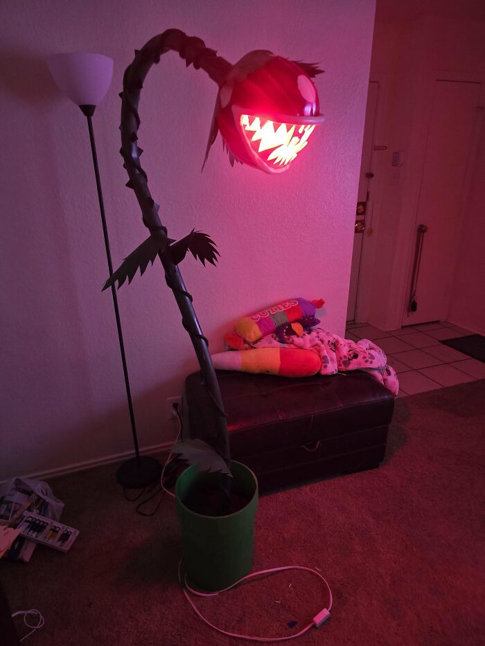 Creepy handmade craft resembling a plant with glowing red eyes and sharp teeth in a living room setting.