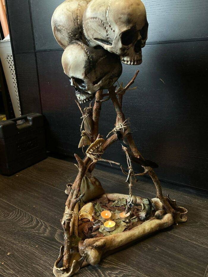 Creepy handmade crafts featuring skulls, bones, and candles arranged on a wooden floor.