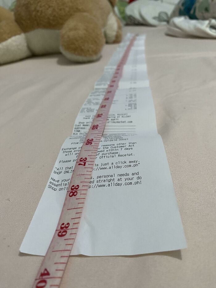 Interesting receipt measured by a tape on a bed with a stuffed toy nearby.