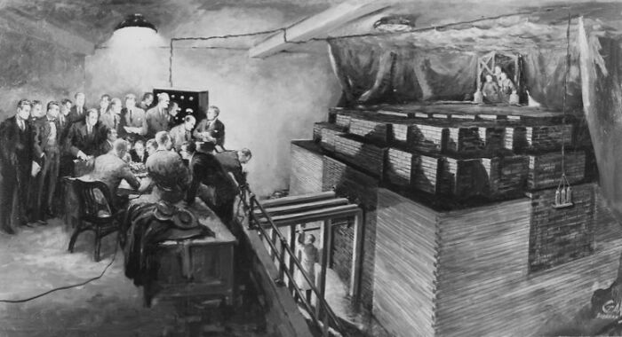 A group of people gathered around a large machine in an underground setting, related to weird government projects.