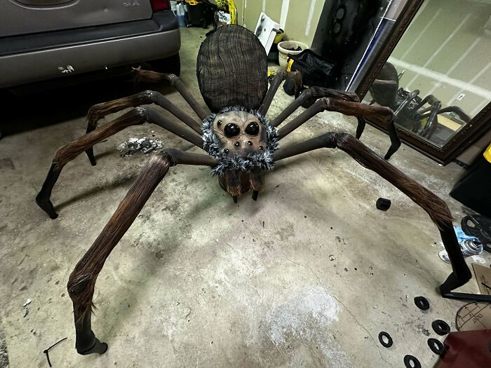 Creepy handmade spider craft with large legs and intricate details in a garage setting.