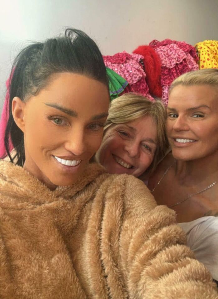 Three people taking a selfie with bright smiles, showcasing heavy airbrush editing in a casual setting.