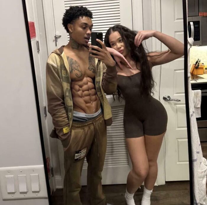 Man and woman posing in a mirror selfie, showcasing exaggerated abs, highlighting Photoshop airbrush techniques.