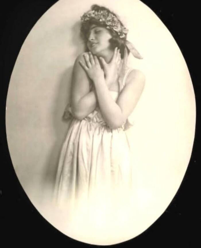 Vintage portrait of a woman in a dress with floral headpiece, evoking timeless elegance from more than a hundred years ago.