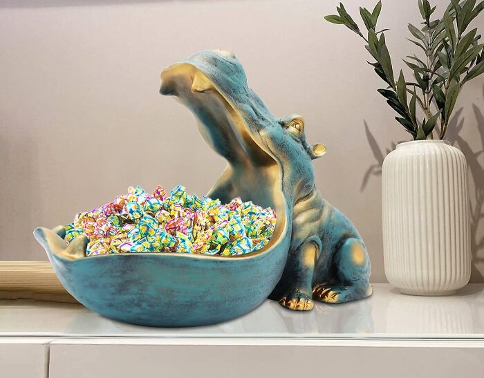 Hippo-shaped candy bowl overflowing with colorful candies, adding unexpected goofiness to home decor.