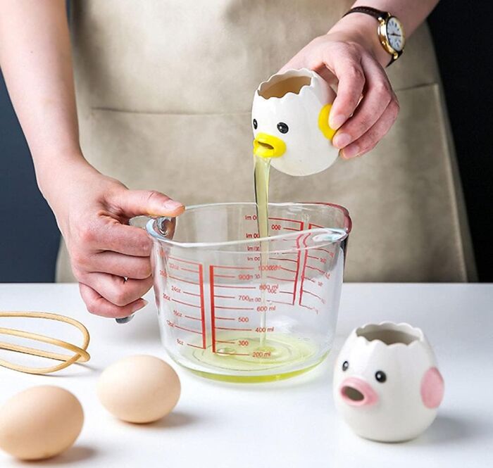 Goofy egg separator used to pour egg whites into a measuring cup, adding humor to cooking.