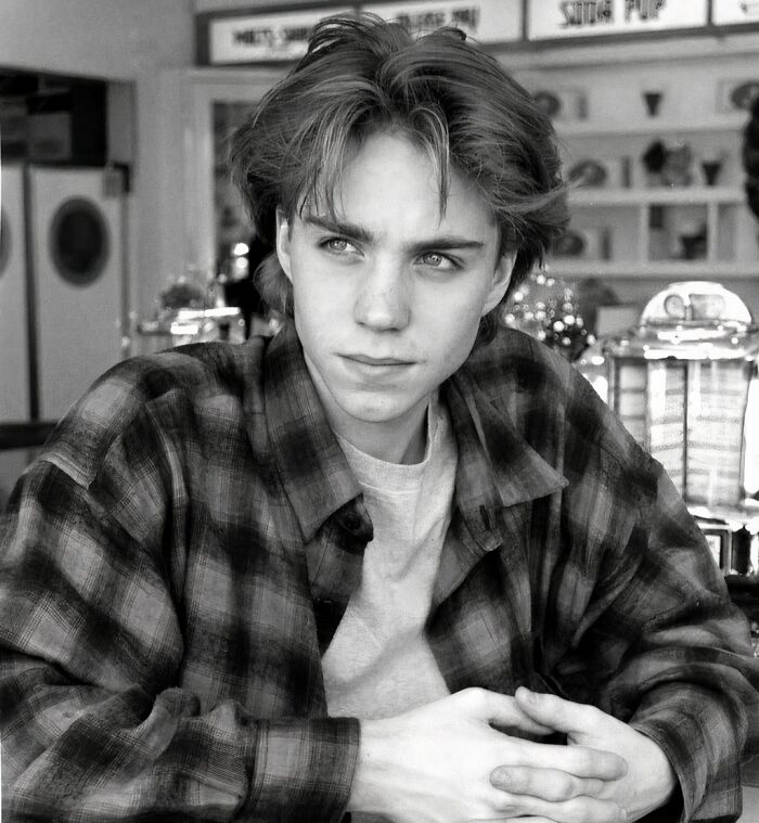 Young person in a '90s diner setting, wearing a plaid shirt.