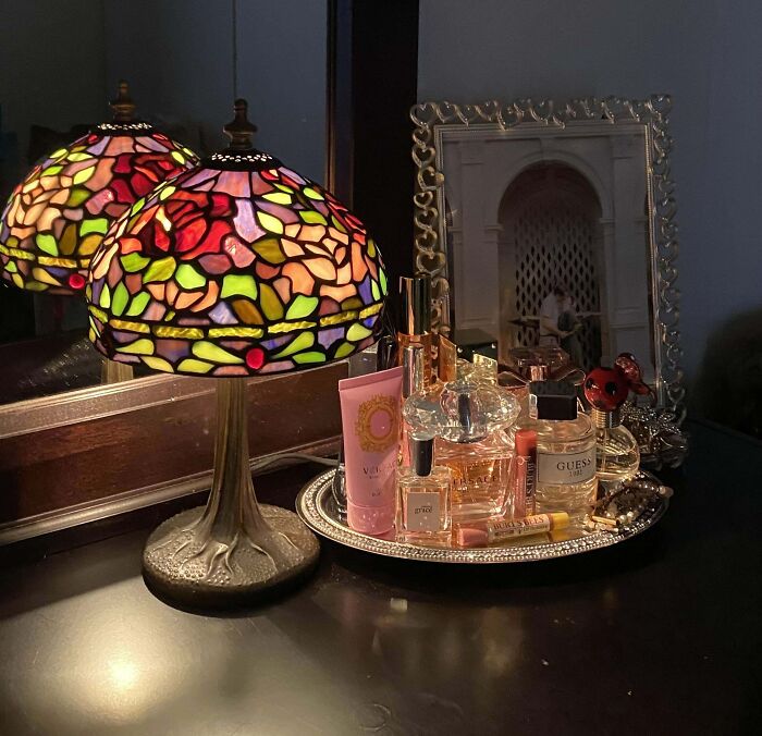 Colorful stained glass lamp with vintage perfume bottles on a mirrored tray, a lucky thrifting find.