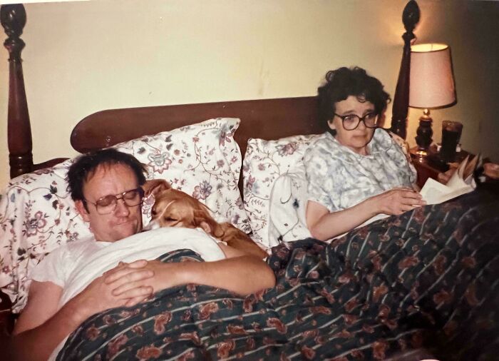 Couple in vintage bedroom setting with dog resting, capturing a candid glimpse into the past not found in history books.