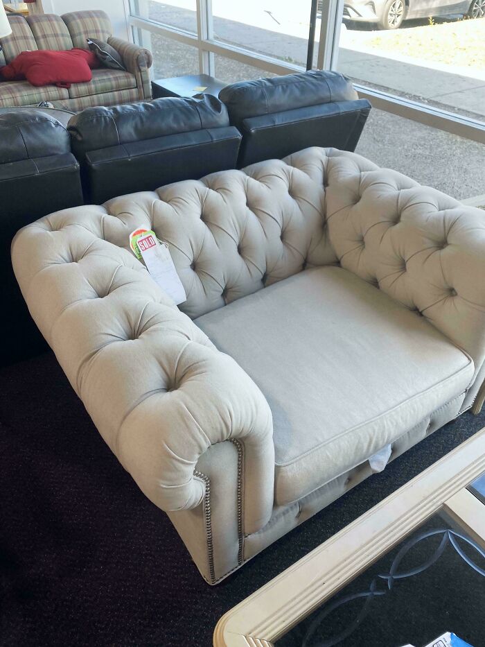 Beige tufted sofa thrift store find with sold tag, displayed among other couches in a thrift store setting.