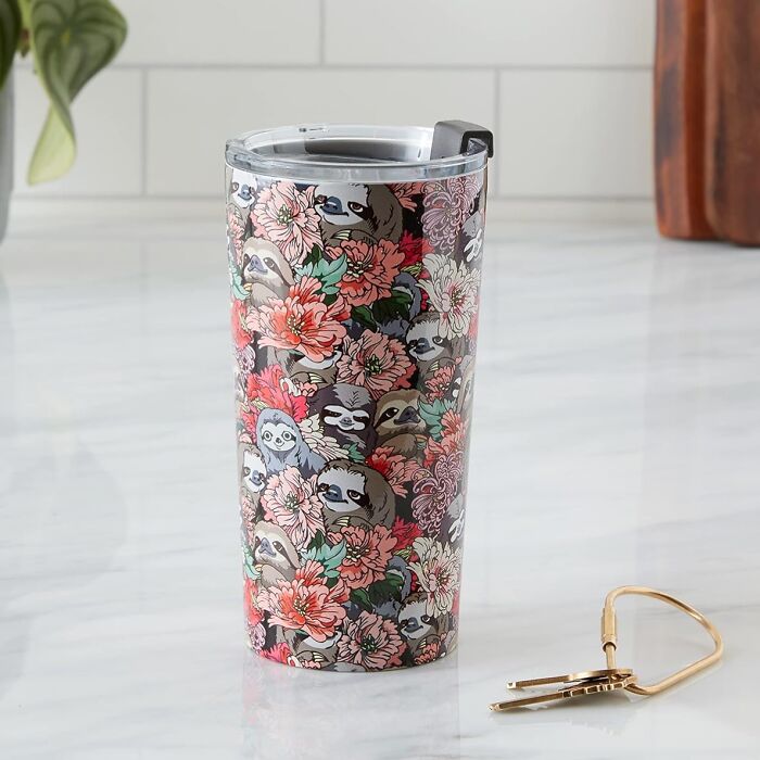 Tumbler with sloth and floral design from Society 6 on a marble countertop next to a gold key.