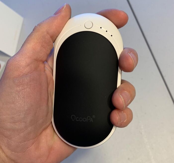 Hand holding a small black and white device to simplify daily life.