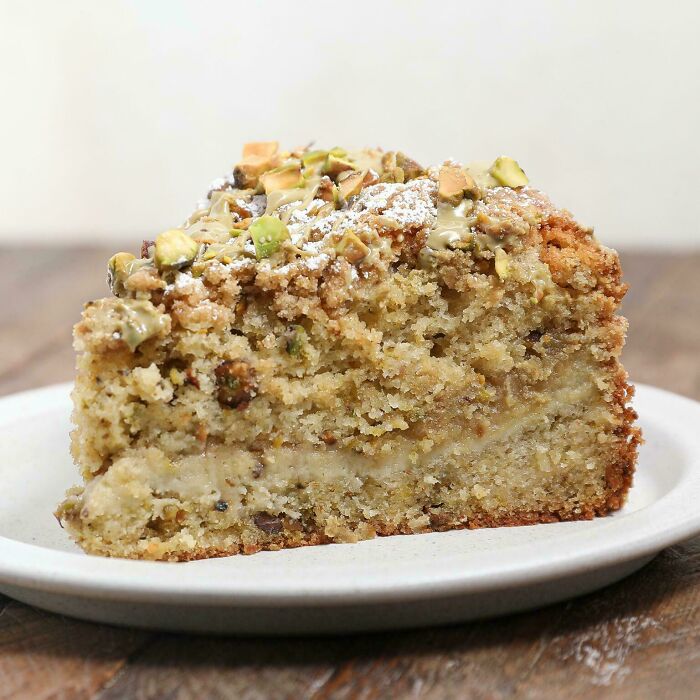 Slice of moist cake topped with chopped nuts and powdered sugar, showcasing one of the incredible bakes.