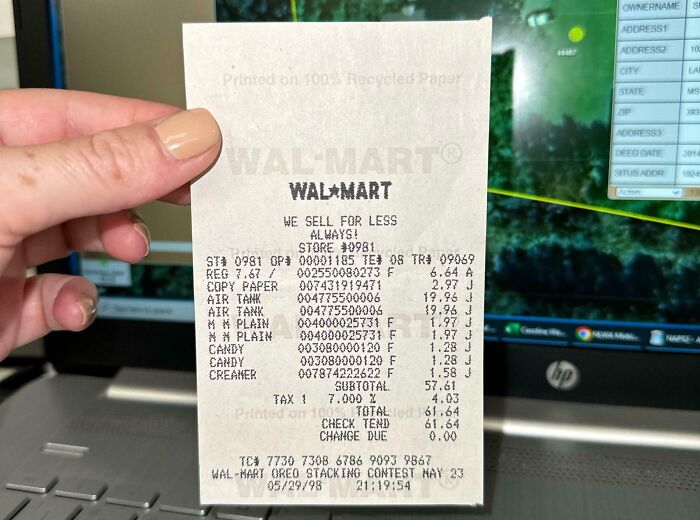 Person holding an interesting receipt from Wal-Mart detailing various purchased items against a laptop background.