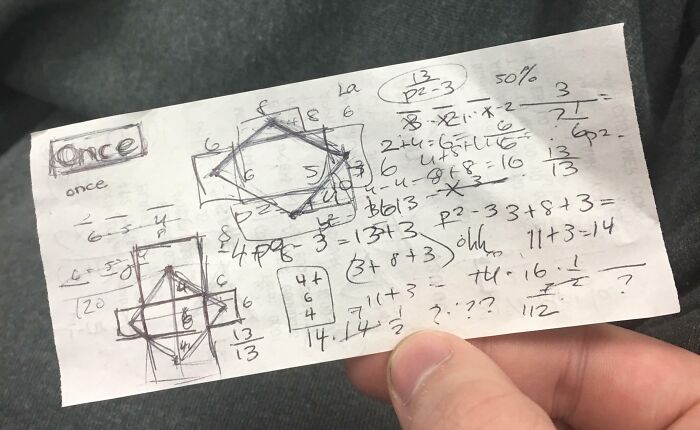 Hand holding an interesting receipt with doodles and math scribbles, showcasing people's unique discoveries.