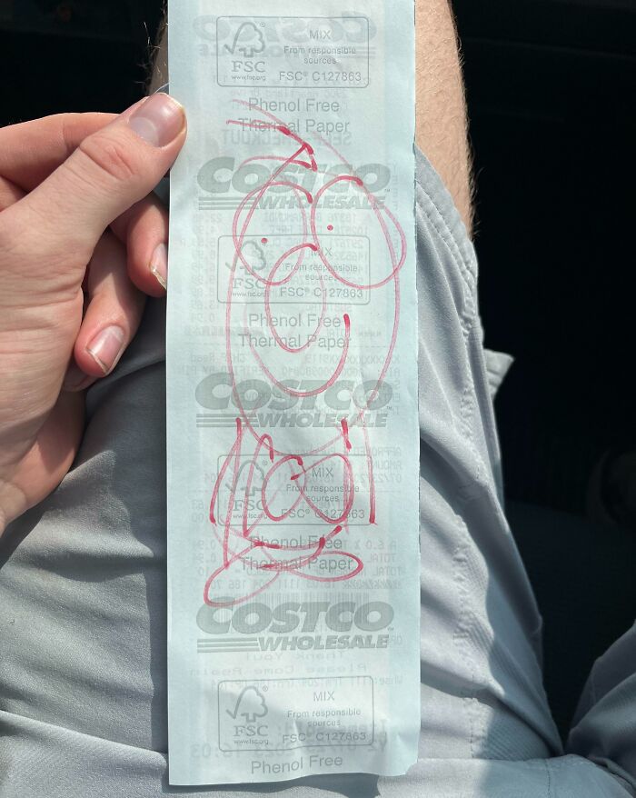Hand holding a Costco receipt with red doodles, representing interesting receipts people found.