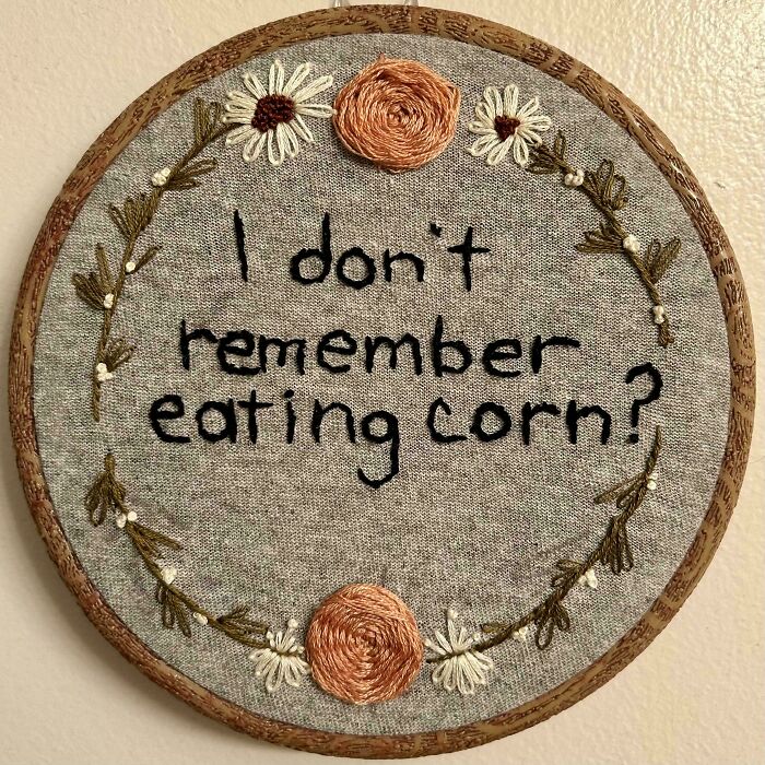 Embroidery hoop art with text and floral designs showcasing incredible and beautiful embroidery skills on gray fabric.