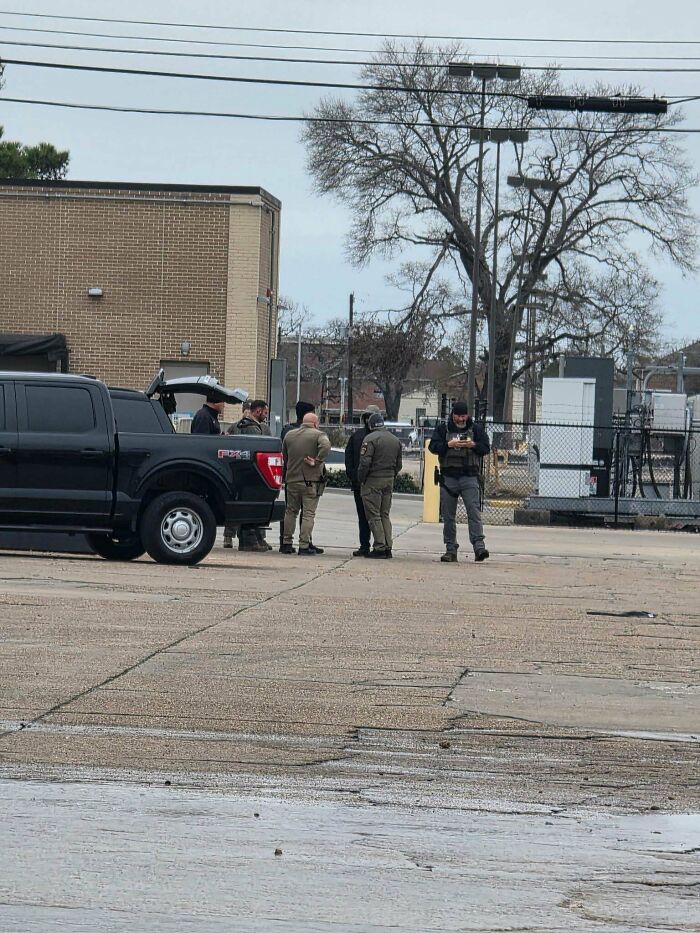 Group of people in an outdoor setting near a black truck, discussing matters during work in the food service industry.