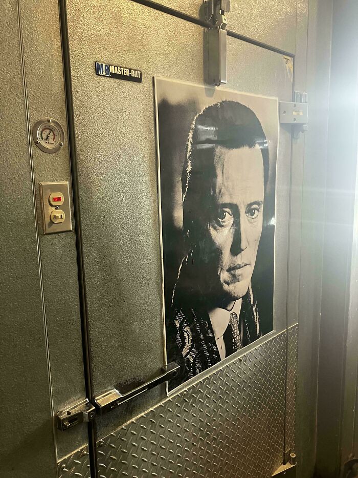 Poster inside a food service industry walk-in cooler, with a black and white face prominently displayed.