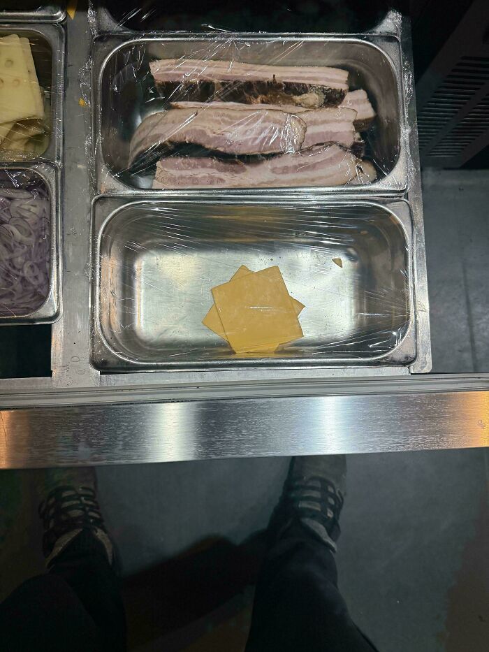 Food service industry: stainless steel containers with sliced meat and cheese in a commercial kitchen setting.