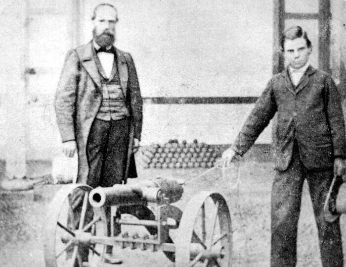 Two inventors pose with their cannon creation, highlighting inventors' surprising outcomes.