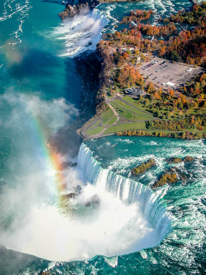 Aerial view of Niagara Falls with mist and rainbow, showcasing one of the unique natural sites only found in Canada.