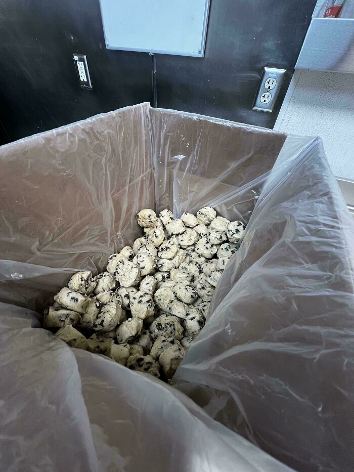 Bin filled with cookie dough balls in a food service kitchen.