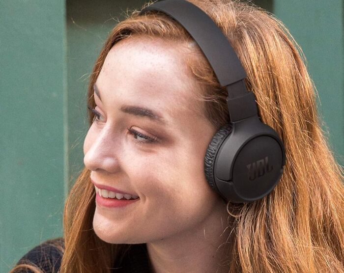 Woman enjoying music with JBL headphones, representing impulse buys worth it.
