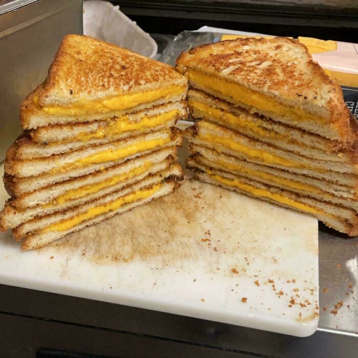 Stacked grilled cheese sandwiches on a cutting board, showcasing food service industry creativity.